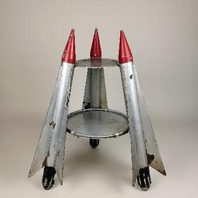 Mesa auxiliar en acero con soportes en forma de cohetes